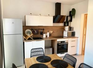 a kitchen with a table and chairs and a white refrigerator at Maison climatisée toute équipée in Montchanin
