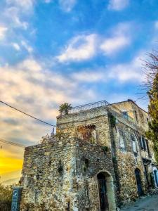 - un vieux bâtiment en pierre avec un palmier au-dessus dans l'établissement La Casa di Vasco Bussana Vecchia, à Sanremo