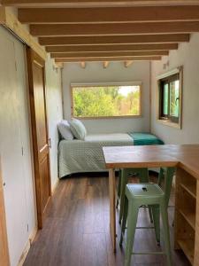 ein kleines Zimmer mit einem Bett, einem Tisch und einem Fenster in der Unterkunft Refugio Huerta Los Maquis in Puerto Guadal