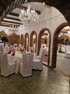 ein Esszimmer mit weißen Tischen, Stühlen und Kronleuchtern in der Unterkunft Hotel & Restaurant Bei Baki in Sehnde
