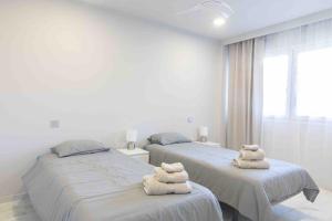 Dos camas en una habitación blanca con toallas. en VILLA rosa BENAHAVIS, en Estepona