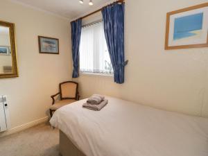 a bedroom with a bed and a chair and a window at 1 South Snowdon Wharf in Porthmadog