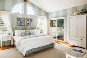 a bedroom with a large bed and two windows at 3485 Avalon by the Sea home in Monterey
