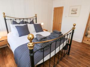 1 dormitorio con cama blanca y negra con almohadas azules en The Snug, en Totland