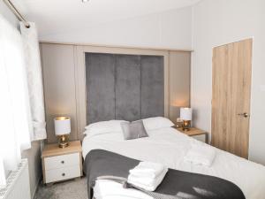 una camera da letto con un grande letto bianco con due lampade di Dershel Lodge a Dumfries