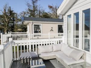 a white porch with a couch on a balcony at Dershel Lodge in Dumfries