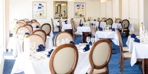 a room filled with tables and chairs with white tablecloths at The Beachcroft Hotel, BW Signature Collection in Bognor Regis