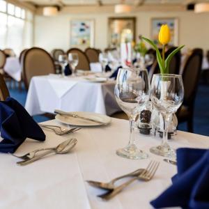 a table with two wine glasses and a yellow flower on it at The Beachcroft Hotel, BW Signature Collection in Bognor Regis