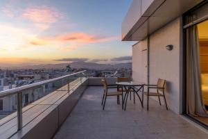 a balcony with a table and chairs and a sunset at Radisson Blu Park Hotel Athens in Athens