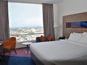 um quarto de hotel com uma cama e uma grande janela em Novotel Taiping em Taiping