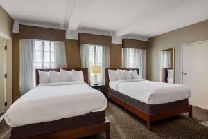 two beds in a hotel room with windows at Best Western Syracuse Downtown Hotel and Suites in Syracuse