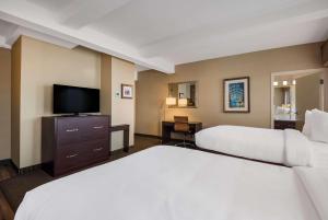 a hotel room with two beds and a flat screen tv at Best Western Syracuse Downtown Hotel and Suites in Syracuse