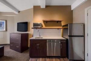 a kitchen with a stainless steel refrigerator and a tv at Best Western Syracuse Downtown Hotel and Suites in Syracuse