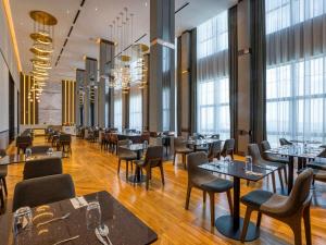 a restaurant with tables and chairs and windows at Mercure Living Putrajaya in Putrajaya