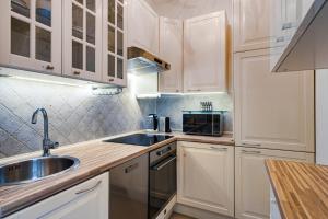 uma cozinha com armários brancos, um lavatório e um micro-ondas em Apartament Wiktoria Wilanów em Varsóvia