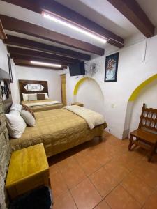 a bedroom with two beds and a tv in it at Hotel Magdalena Colonial in Guanajuato