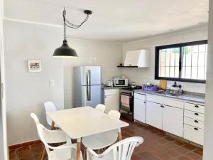 eine Küche mit einem weißen Tisch und einem weißen Kühlschrank in der Unterkunft Hermosa casa céntrica in San Antonio de Areco