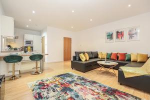 a living room with a black couch and a kitchen at Riverside Modern 2 Bedroom Flat in Glasgow