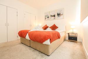 a bedroom with a large bed with orange sheets at Riverside Modern 2 Bedroom Flat in Glasgow