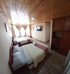 a bedroom with two beds in a room with a wooden ceiling at Hotel Buenaventura in Pasto