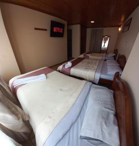 a group of three beds in a small room at Hotel Buenaventura in Pasto