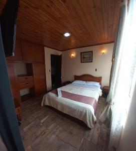 um quarto com uma cama e um tecto de madeira em Hotel Buenaventura em Pasto