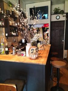 a bar with a vase of flowers on a counter at Backstage Party Hostel & Bar in Osaka