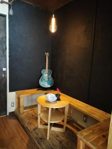 a table with a guitar on a wall and a table with a stool at Backstage Party Hostel & Bar in Osaka