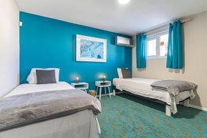 two beds in a room with blue walls at Ojanea Home in Palm-Eagle Beach