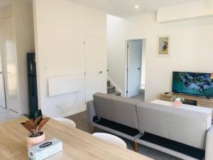 sala de estar con sofá y mesa en Cozy Brand New Townhouse 24, en Auckland