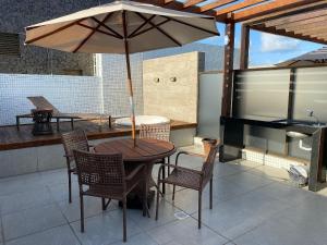 a table and chairs with an umbrella on a patio at Bela Hospedagem - EcoSummer Cobertura em Tambaú in João Pessoa