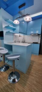 a kitchen with blue cabinets and two bar stools at Mistow BriaScarlet Condo in Cagayan de Oro