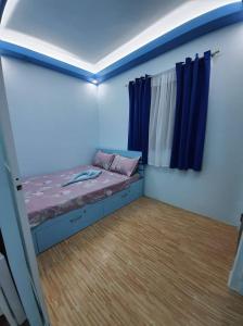 a small bedroom with a bed and blue curtains at Mistow BriaScarlet Condo in Cagayan de Oro