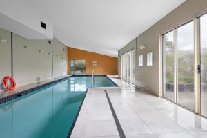 una piscina in un edificio con una grande finestra di Monument Chalet in Crakenback Resort a Crackenback