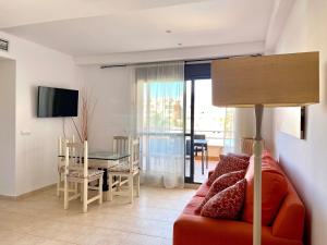 salon z czerwoną kanapą i stołem w obiekcie Apartment near beach with pools in Spain w mieście Los Amarguillos