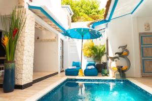 勒吉安的住宿－Shray Villa. Legian，一座房子旁带蓝伞的游泳池