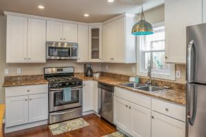 una cocina con armarios blancos y electrodomésticos de acero inoxidable en 3788 The Seagull's Nest home en Pacific Grove
