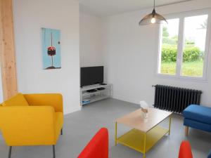 uma sala de estar com cadeiras amarelas e azuis e uma televisão em Cottage, St Pabu em Kervasdou