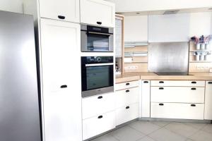 una cocina blanca con armarios y electrodomésticos blancos en Villa Nirvana vue Mer piscine plage de Petit Havre a 200 metre, en Le Gosier