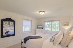 a white bedroom with a bed and a mirror at 3786 Adobe by the Sea home in Pebble Beach