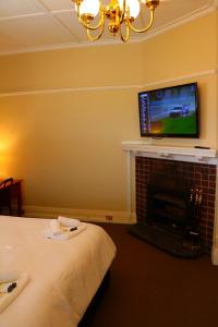Palace Hotel Mortlake Sydney في سيدني: غرفة نوم مع موقد وتلفزيون على الحائط