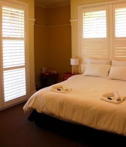 a bedroom with a large white bed with windows at Palace Hotel Mortlake Sydney in Sydney