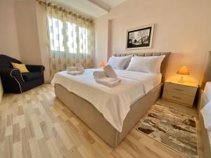 a bedroom with a large white bed and a chair at City Centre Big Art'partment Heart of The Capital in Tirana