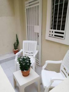 um alpendre com cadeiras brancas e um vaso de plantas em Hermoso y cómodo apartamento familiar en Ciudad Juan Bosch em Los Paredones
