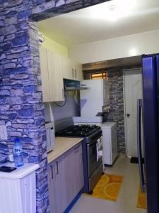 a kitchen with white cabinets and a stone wall at Hermoso y cómodo apartamento familiar en Ciudad Juan Bosch in Los Paredones