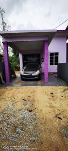 a car parked under a garage with purple pillars at Homestay Padang Air in Kampong Tuan Mandak