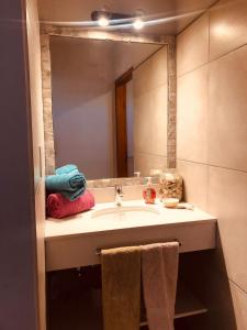 a bathroom with a sink with a mirror and towels at La Pasionaria Casa de Campo in Agua de Oro