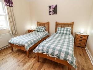 two twin beds in a room with wooden floors at Houghton North Farm Cottage in Heddon on the Wall