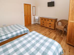 a bedroom with two beds and a dresser and a television at Houghton North Farm Cottage in Heddon on the Wall