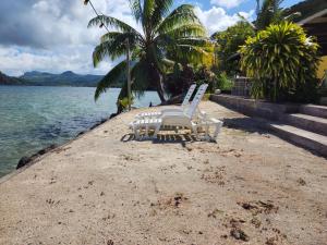 two chairs sitting on a beach next to the water at VILLA DE LA BAIE RAIATEA in Uturoa